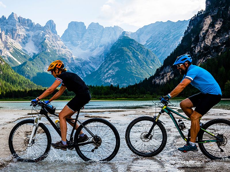 Coppia in bici su sentiero alpino con vista montagne