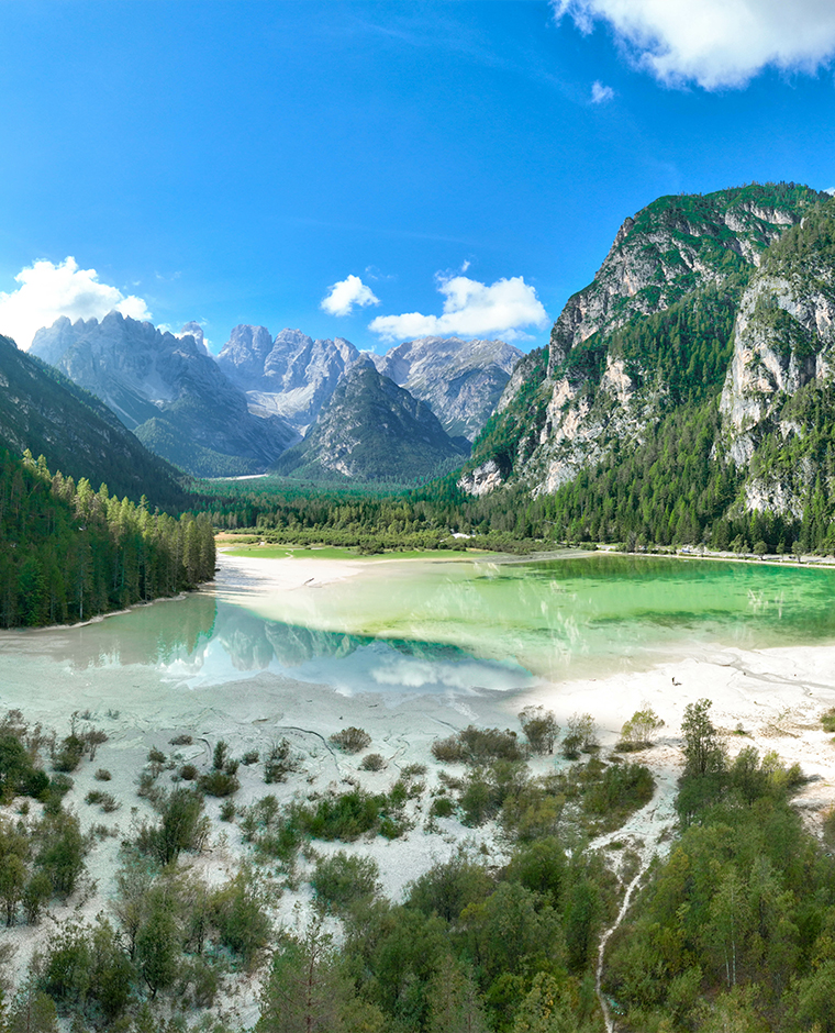 Panoramica aerea dall'alto del paesaggio sulle Dolomiti di Sesto durante gironata di sole con cielo limpido blu