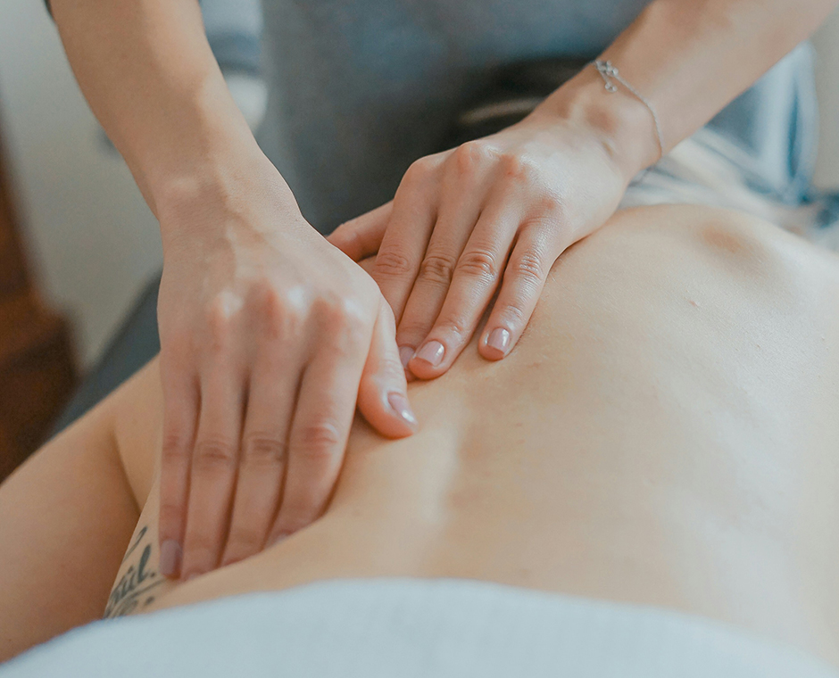 Donna che massaggia la schiena di una persona, trattamento benessere