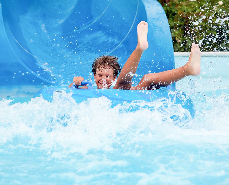 un bambino di 8 anni gira nel parco acquatico su cerchi gonfiabili su scivoli d'acqua.