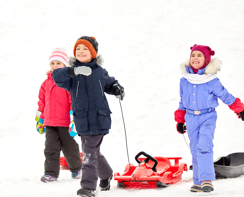 Gruppo di bambini felici con slitta in inverno