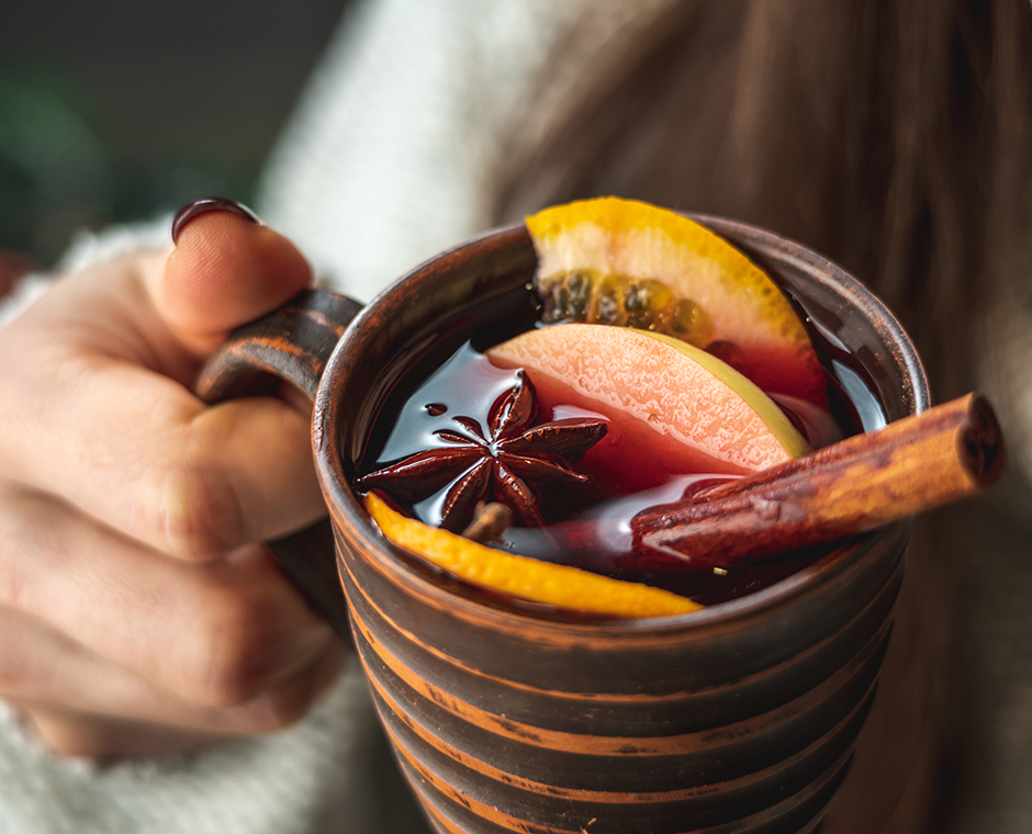 Donna con un caldo maglione beve un aromatico vin brulé caldo. 