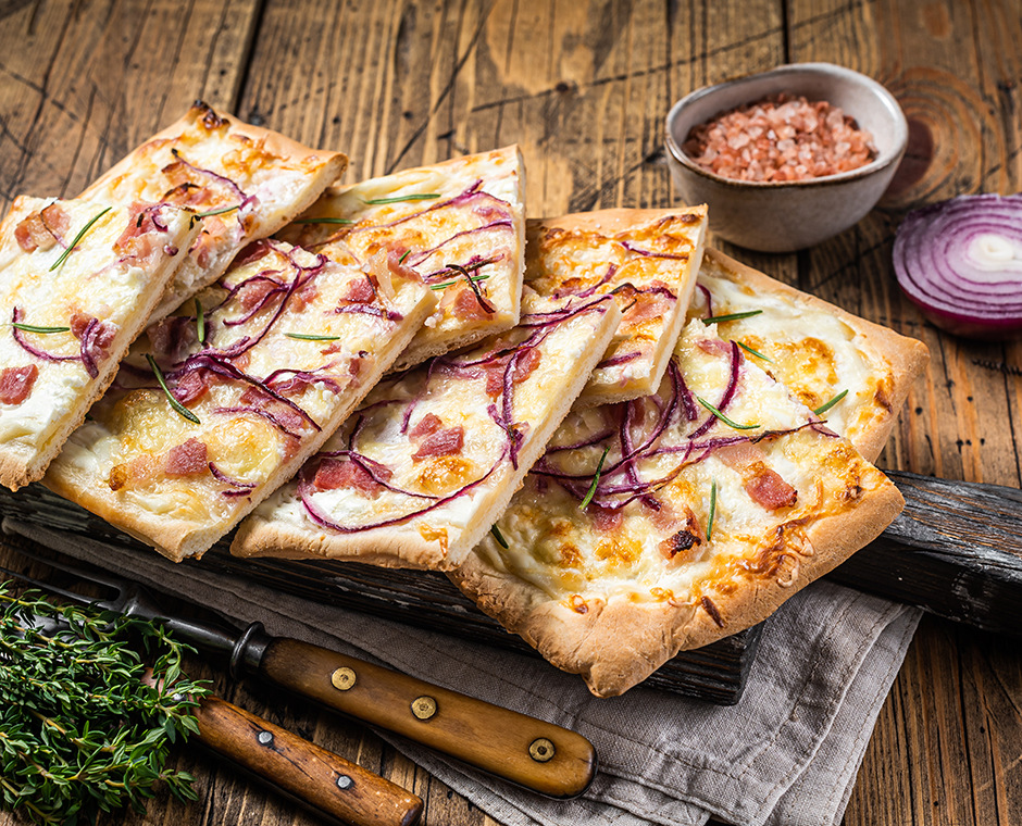 Flammkuchen o tarte flambee con crema di formaggio, pancetta e cipolle.