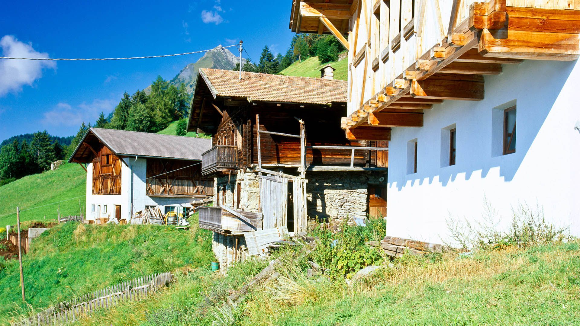 Antichi masi in legno e pietra in Val Passiria con sfondo montano e paesaggio alpino estivo