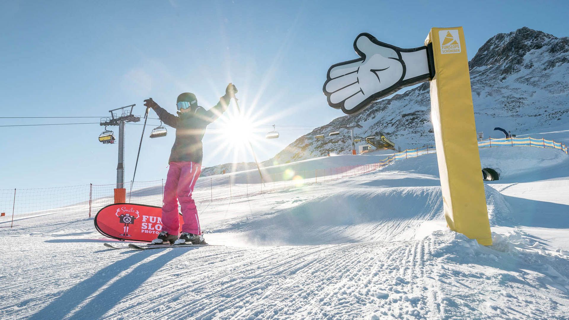 Sciatore al sole sulla pista di Belpiano con seggiovia e cartello Fun Slope sullo sfondo