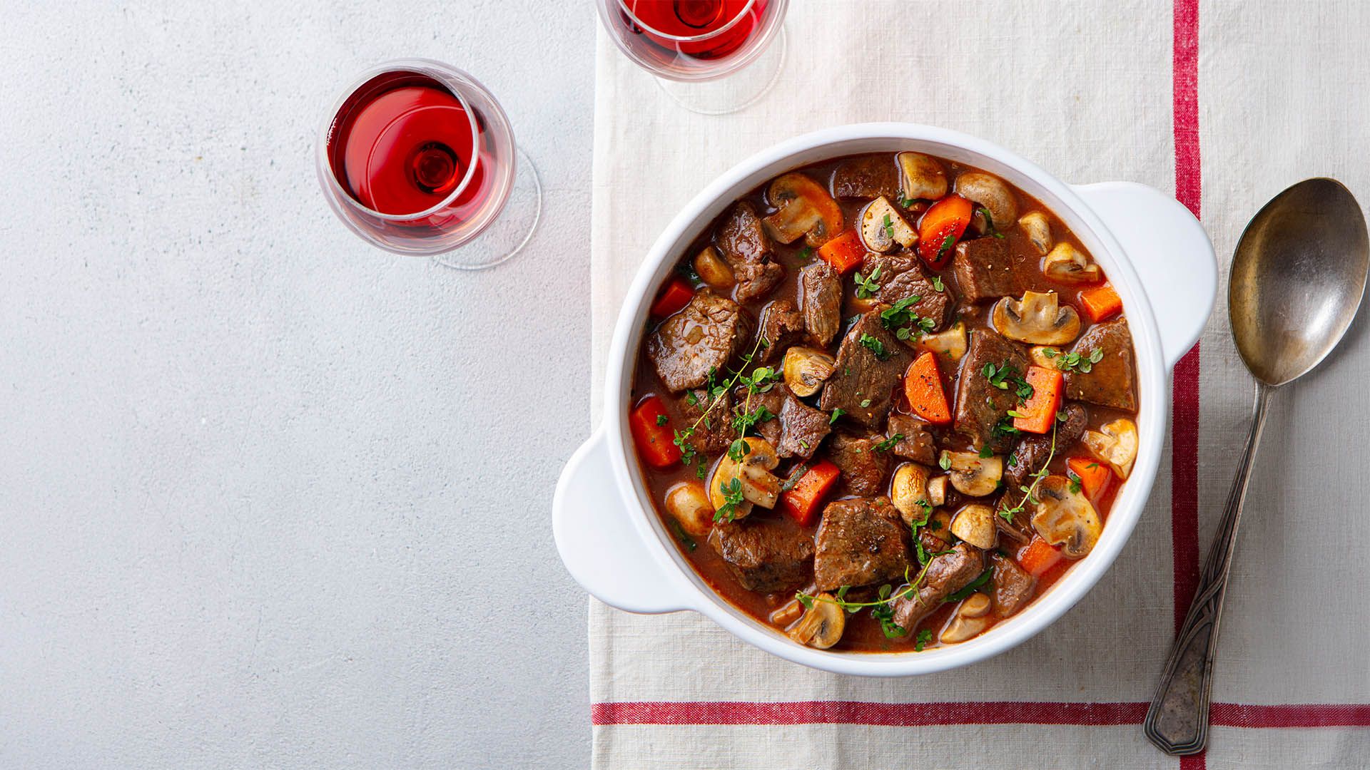 Spezzatino di manzo con verdure servito con vino rosso.