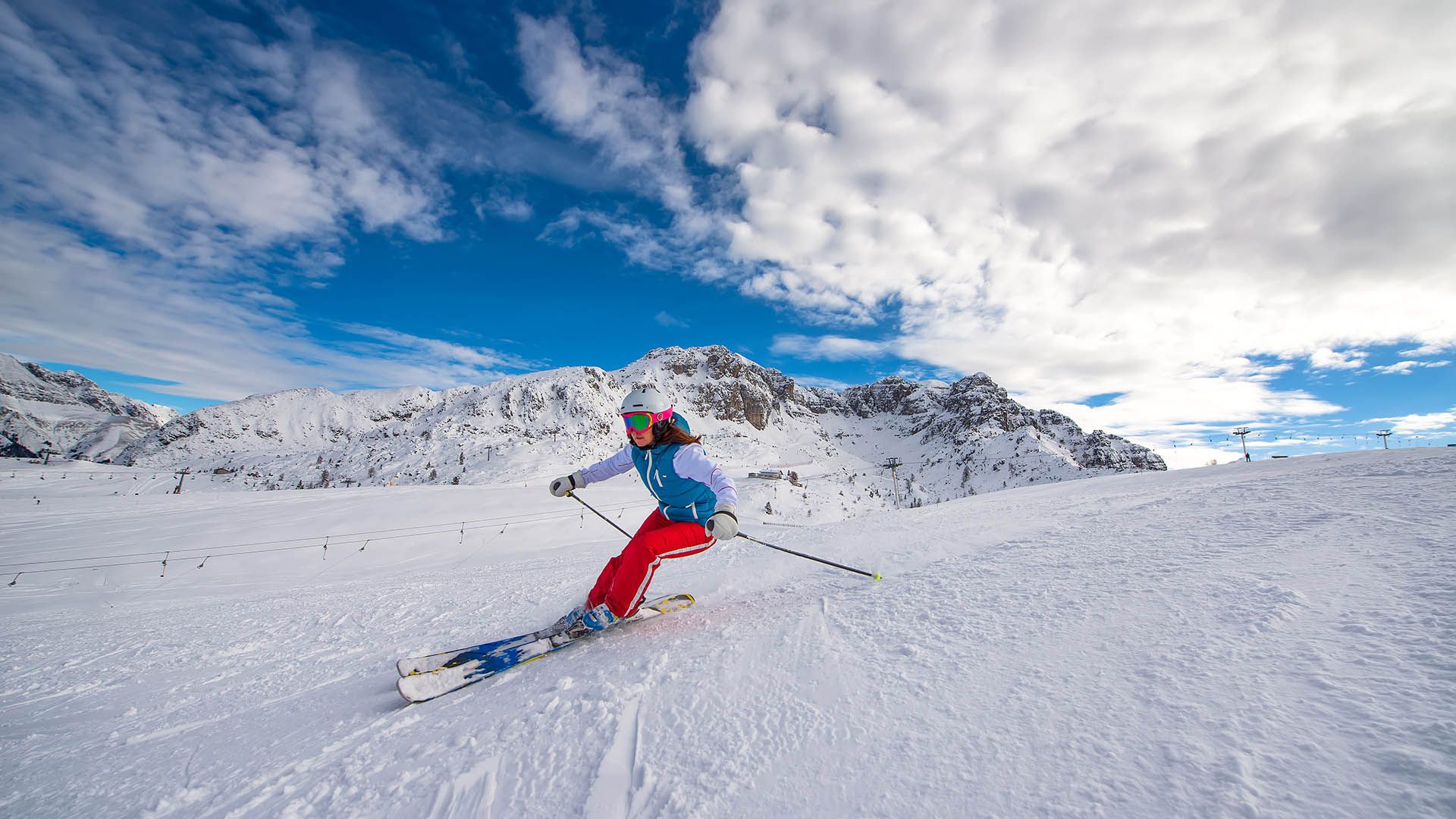 Sciatrice in azione su una pista innevata con le montagne sullo sfondo in Alto Adige.