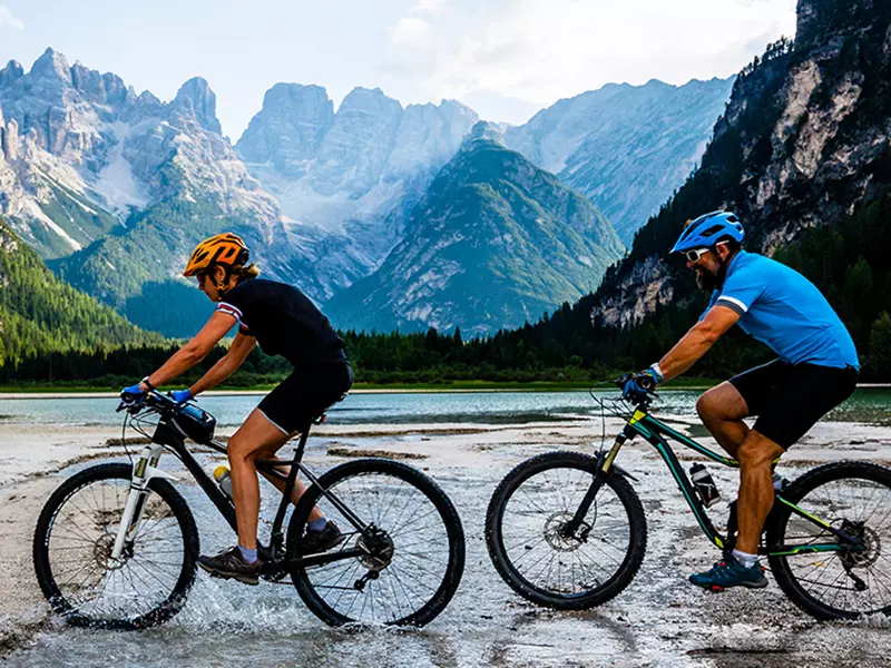 Coppia in bici su sentiero alpino con vista montagne